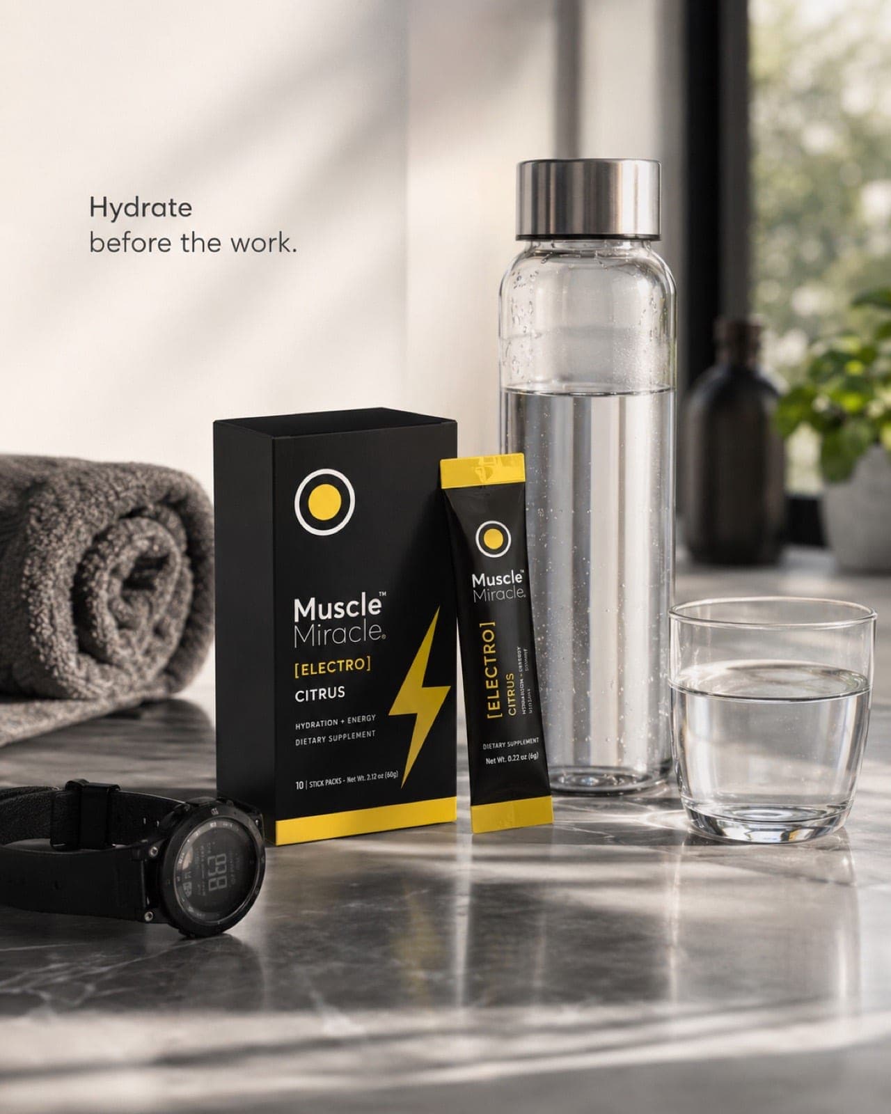 A Muscle Miracle Electrolytes Citrus pack and glass bottle of water on a kitchen counter in the morning