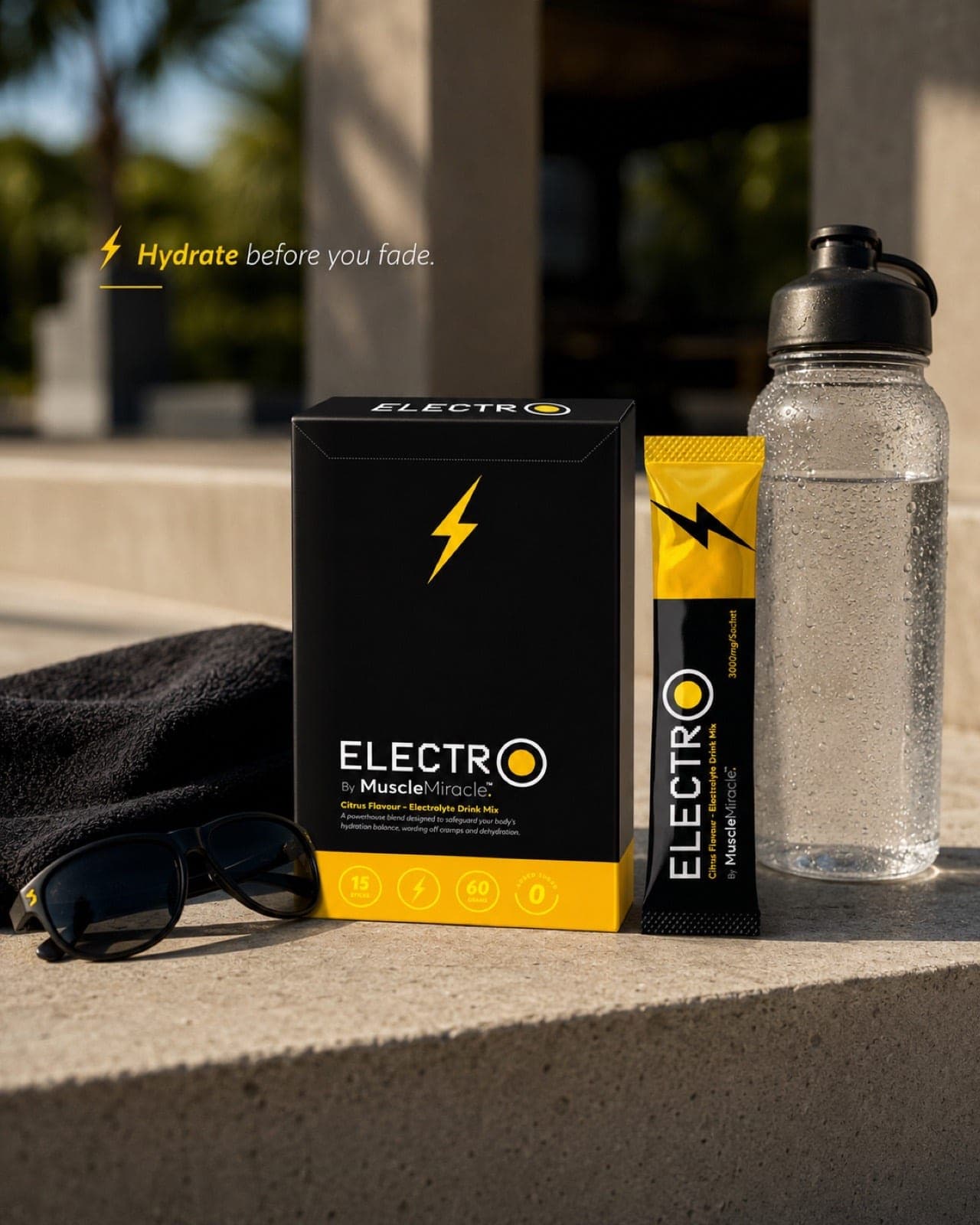 Muscle Miracle Electrolytes Citrus pack, sachet and water bottle on a sunlit step outdoors