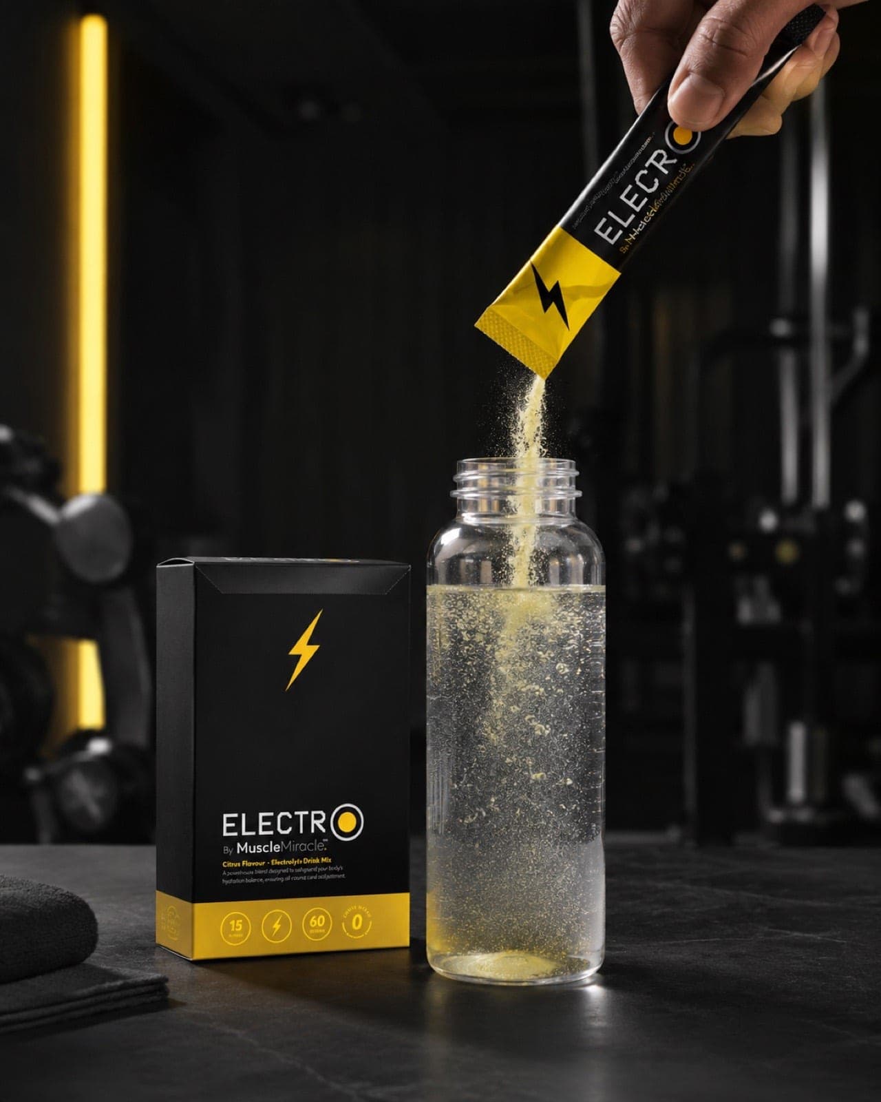 A citrus Electrolytes sachet being poured into a water bottle in a gym