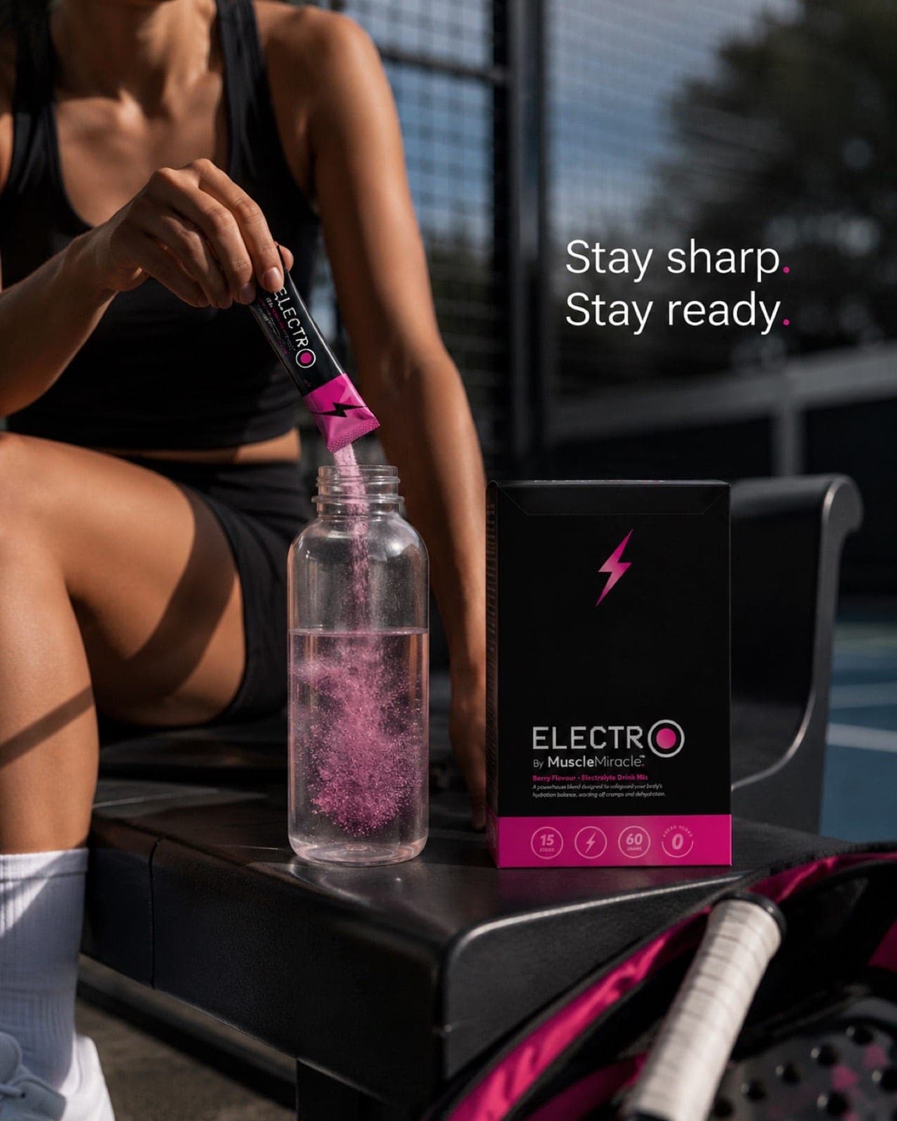 An athlete stirring a Muscle Miracle Electrolytes Berry sachet into a bottle courtside between points