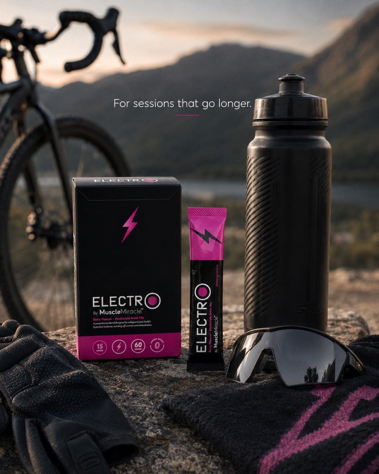 Muscle Miracle Electrolytes Berry pack and bottle on a rock beside a gravel bike at sunset