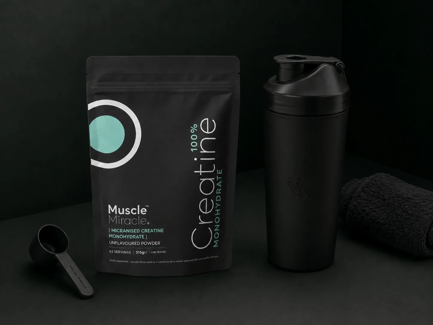 Muscle Miracle Creatine Monohydrate pouch beside a black shaker and scoop